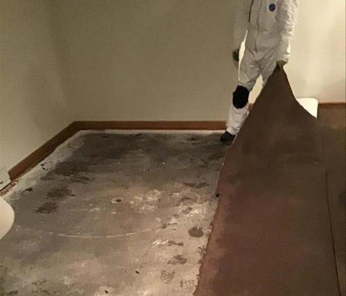 Concrete is exposed while the carpet is pulled back.