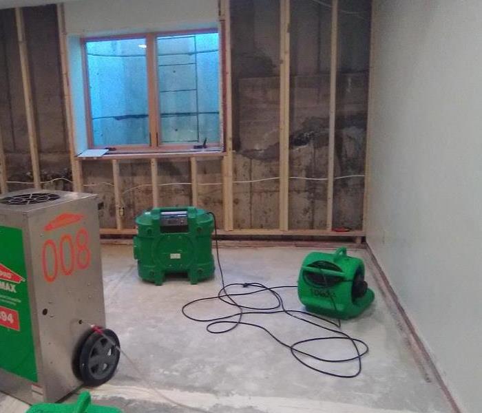 Stripped room with green air movers and scrubbers on the floor. 