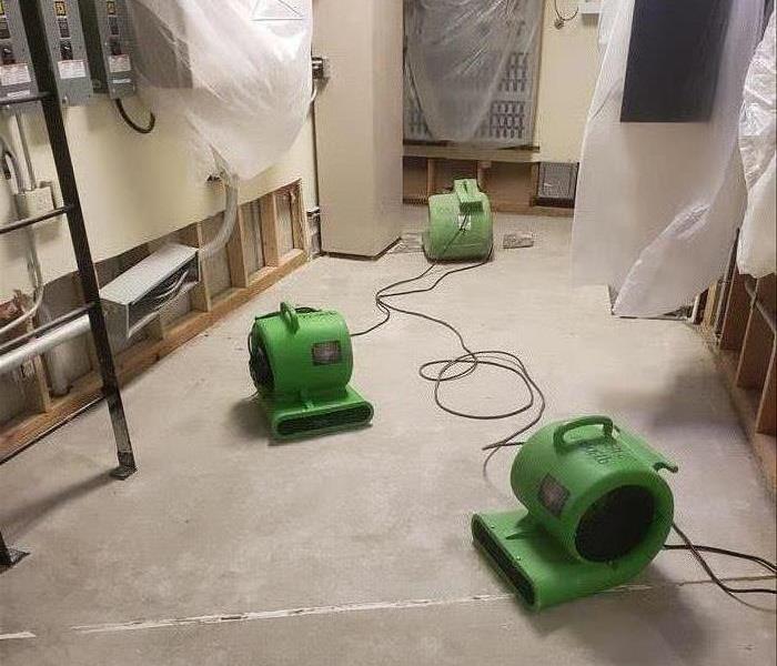 Green air movers on a protective floor sheet. 