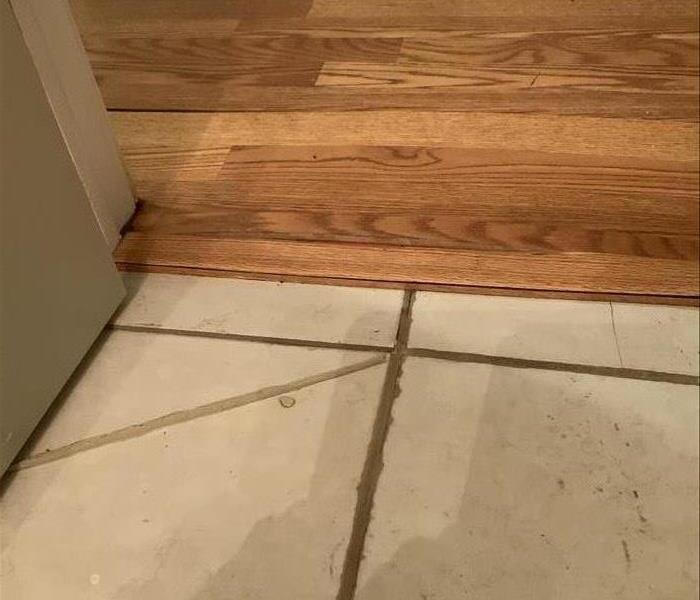 Cream tile and wood floor meet. 