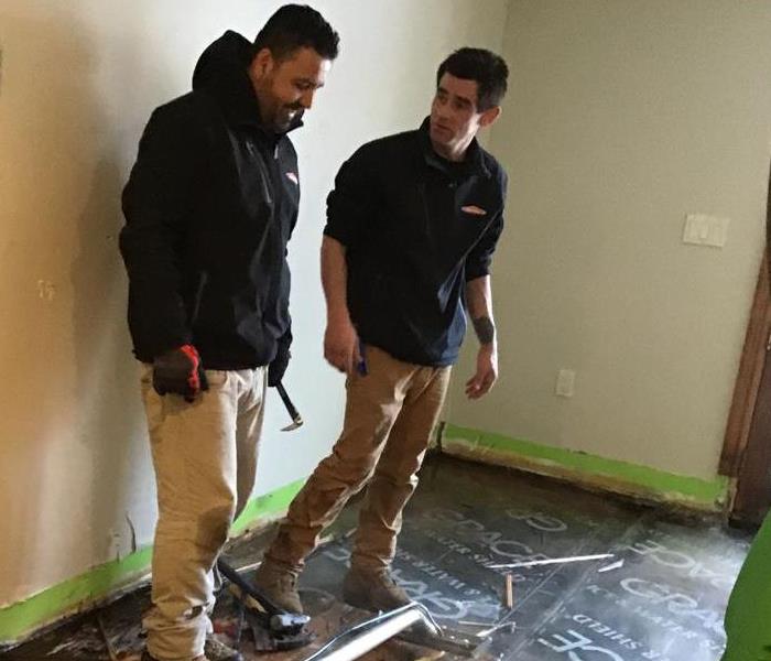 two employees working on removing a water damaged floor.